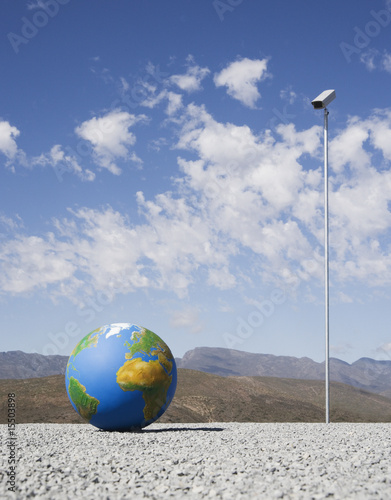 Foto: Globe on gravel with surveillance camera outdoors Globe on gravel with surveillance camera outdoors