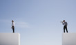 Businessman with megaphone on wall shouting at businessman on wall with gap