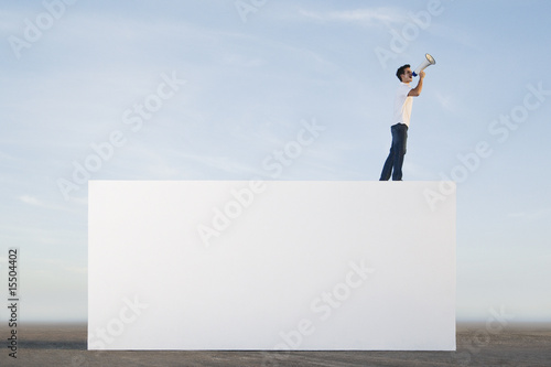 Photo: Man standing on wall outdoors with megaphone Man standing on wall outdoors with megaphone