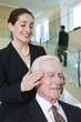 Businesswoman massaging senior executive's headache.