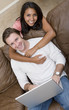A woman hugging her boyfriend while he is on the computer A woman hugging her boyfriend while he is on the computer