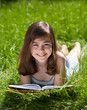 Girl reading book lying on green meadow Girl reading book lying on green meadow