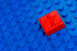 Roter Bauklotz in einem Feld blauer