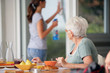 Photo : Femme agée prenant son petit déjeuner observant une femme Femme agée prenant son petit déjeuner observant une femme