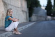 Very pretty young woman sitting on the sidewalk