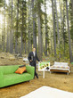 A realtor with home furnishings outdoors in the woods