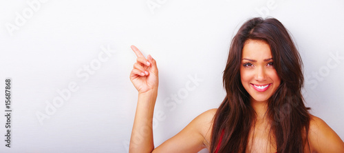 Photo : Happy beautiful girl pointing on to white background Happy beautiful girl pointing on to white background