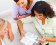 Happy young girls looking at her friend opening a gift box