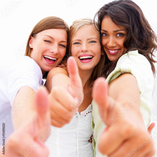 Foto: Closeup portrait of happy young friends showing thumbs up Closeup portrait of happy young friends showing thumbs up