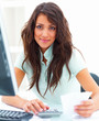 Smiling young business woman sitting while using calculator