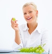 Beautiful smiling blond girl eating grapes