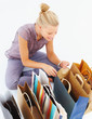 Attractive woman sitting with shopping bags on white background