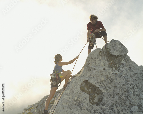 Foto: A man helping a woman climber to the top of the mountain A man helping a woman climber to the top of the mountain