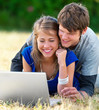 Foto: Happy young couple using laptop at park Happy young couple using laptop at park