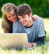 Happy young couple using a laptop at park