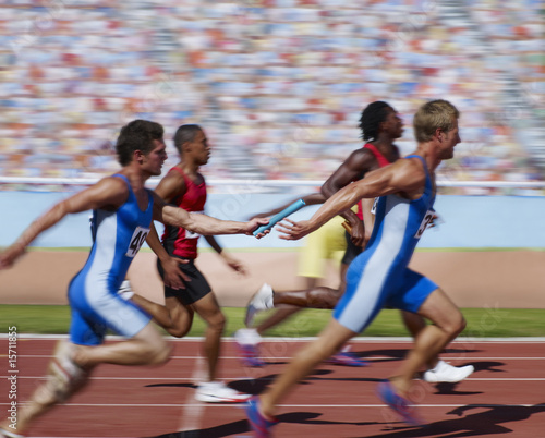 Photo: Racers running on track with relay baton Racers running on track with relay baton