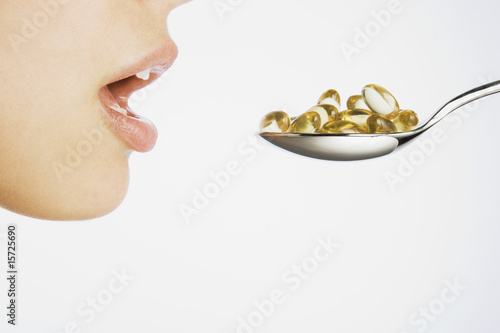 Photo: Woman taking a spoonful of pills Woman taking a spoonful of pills