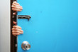 Hands behind a blue door