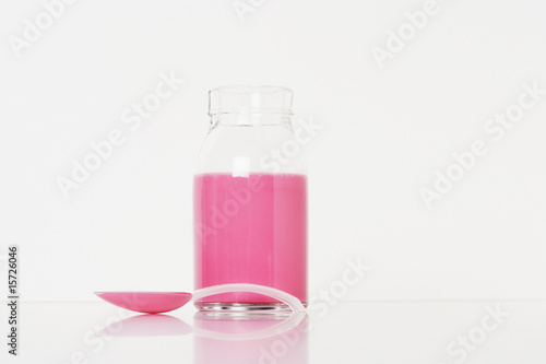 Photo: A container of medicine with a spoonful in front of it A container of medicine with a spoonful in front of it