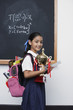 Girl with trophy by blackboard in classroom