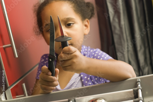 Foto: Danger accident domestique - jeune fille touchant aux couteaux Danger accident domestique - jeune fille touchant aux couteaux