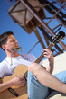 guy plays guitar and  lip accordion sitting on sand