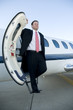 Businessman standing on the steps of corporate jet