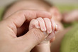 Newborn baby holding his fathers hand