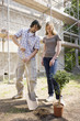 Young couple at construction site planting a tree