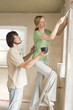 Young couple at site, woman using a putty knife, side view