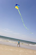 Germany, Baltic sea, Boy (8-9) flying kite at beach