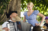 Foto: Germany, Bavaria, Upper Bavaria, Senior man in traditional costume playing accordion in beer garden Germany, Bavaria, Upper Bavaria, Senior man in traditional costume playing accordion in beer garden