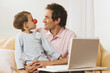 Foto: Father and son (4-5) at laptop, boy wearing clown nose Father and son (4-5) at laptop, boy wearing clown nose
