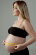side pose of pregnant female measuring her belly