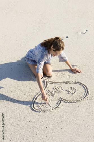 Photo: Woman drawing a heart shape on the beach Woman drawing a heart shape on the beach