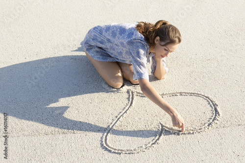 Photo: Woman drawing a heart shape on the beach Woman drawing a heart shape on the beach