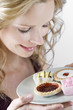 A portrait of a young woman holding a plate of assorted cakes