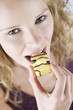 A portrait of a young woman eating a cake with yellow icing