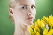 A young woman holding a bunch of yellow tulips looking down
