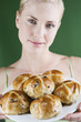 A young woman holding a plate of hot cross buns
