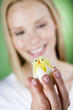 A young woman looking at an Easter chick toy, close-up