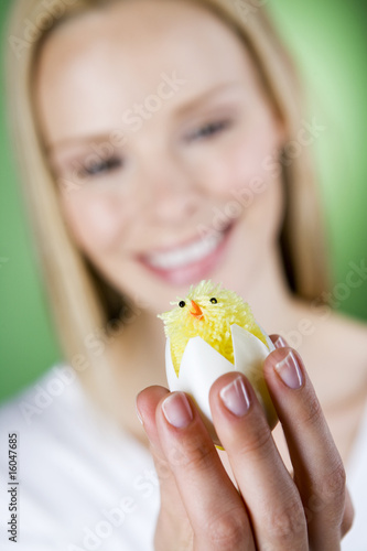 Photo: A young woman looking at an Easter chick toy, close-up A young woman looking at an Easter chick toy, close-up