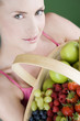 A young woman holding a basket of fruit, smiling