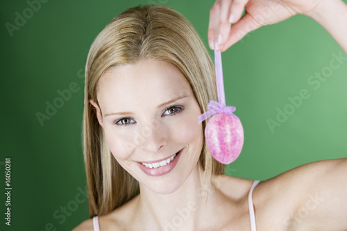 Photo: A portrait of a young blonde woman holding a pink Easter egg A portrait of a young blonde woman holding a pink Easter egg