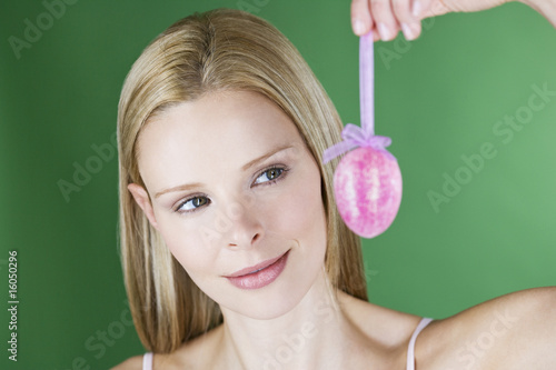 Photo: A portrait of a young blonde woman holding a pink Easter egg A portrait of a young blonde woman holding a pink Easter egg
