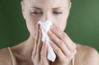 A portrait of a young woman blowing her nose