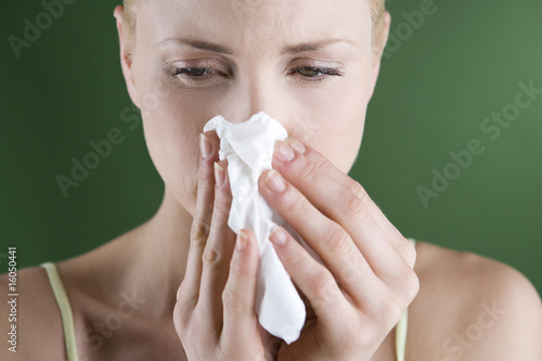 Foto: A portrait of a young woman blowing her nose A portrait of a young woman blowing her nose