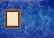 Grunge blue stucco wall with empty picture frame