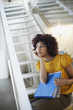 Businesswoman in office space with binders at bottom of staircase