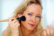 Closeup portrait of a beautiful young woman applying make up